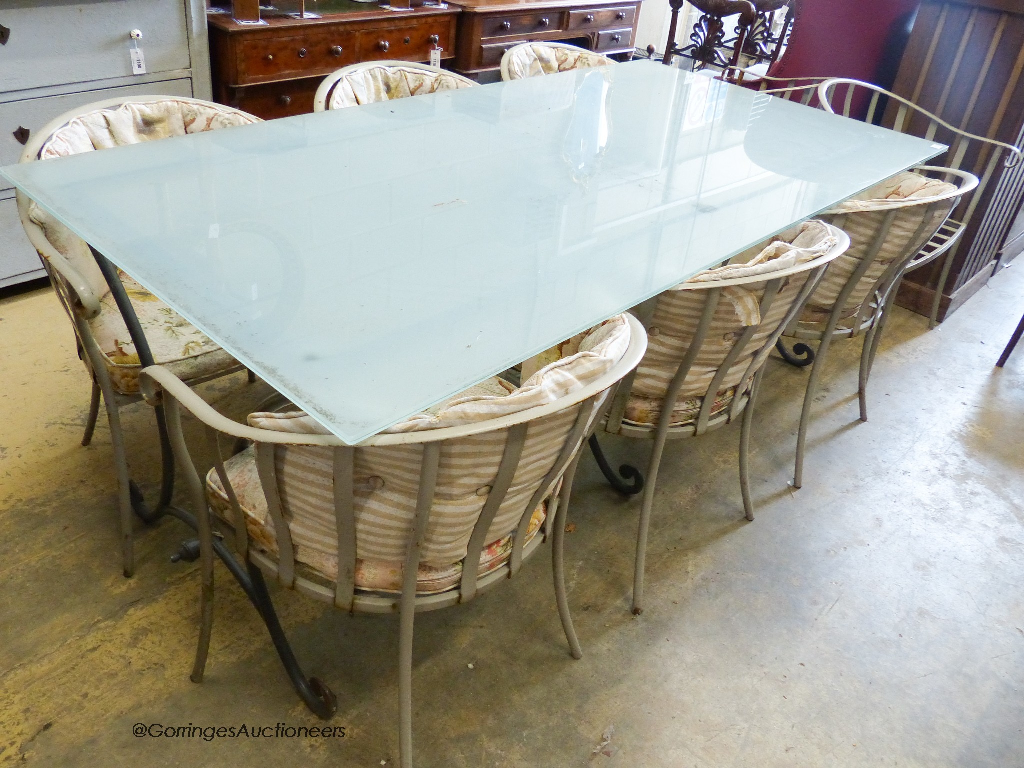 A rectangular glass topped wrought iron garden table and eight chairs. Table, 200x100x75cm.